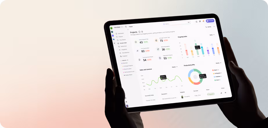 Hands holding a tablet displaying a project management dashboard with charts, project stats, and ongoing tasks.