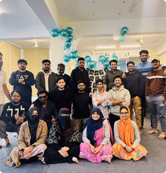 Group of young adults posing indoors with teal and white balloons and a Happy New Year sign in the background.