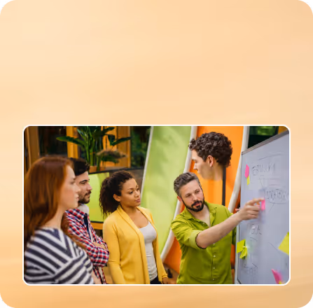 A man in a green shirt presenting ideas on a whiteboard with colorful sticky notes to an attentive group of three people.
