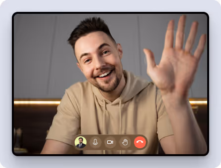 Smiling man with beard waving during a video call interface on screen.